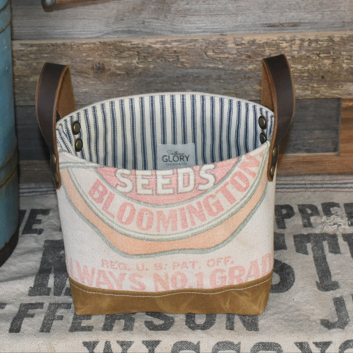 Handmade storage basket from a vintage Funk's Farm Seed Sack. Features a waxed canvas boot & two leather lug handles. Lined with mattress weight blue ticking fabric.